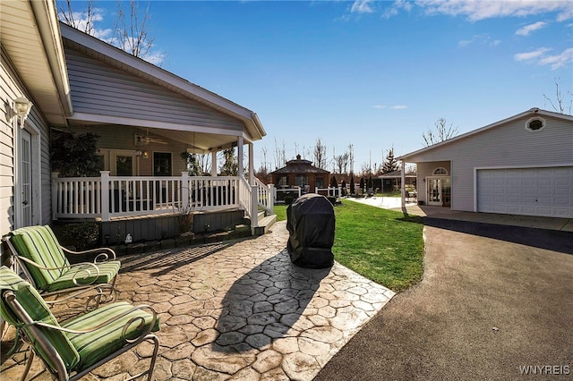 view of patio / terrace featuring a garage, a porch, and ceiling fan