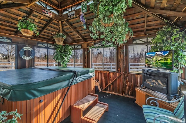 unfurnished sunroom with wooden ceiling, a jacuzzi, vaulted ceiling with beams, and a wood stove