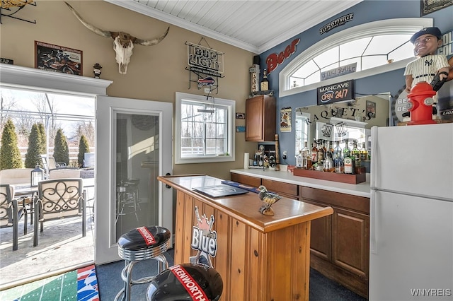 kitchen with a center island, light countertops, ornamental molding, brown cabinets, and freestanding refrigerator