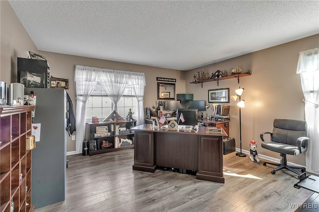 office with baseboards, a textured ceiling, and light wood-style floors