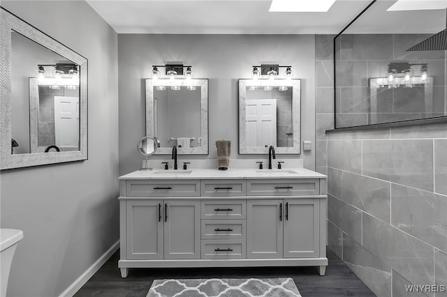 full bathroom with a sink, baseboards, wood finished floors, and double vanity