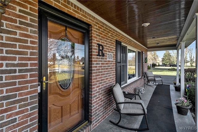 property entrance with covered porch and brick siding