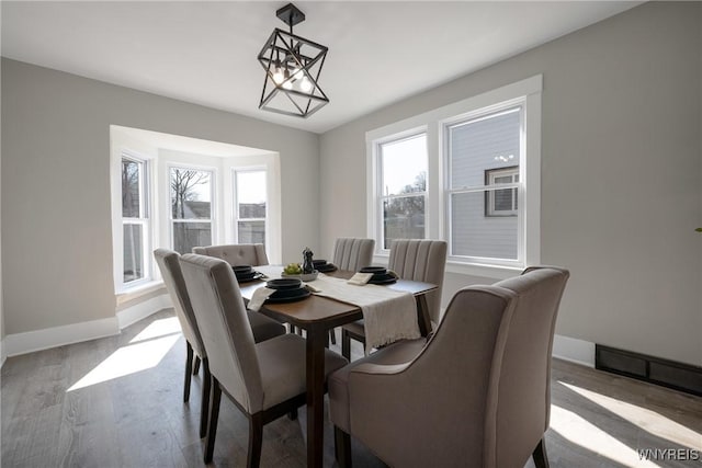 dining area with a chandelier, baseboards, and wood finished floors