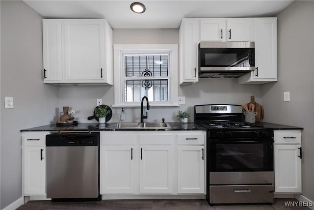 kitchen with white cabinets, appliances with stainless steel finishes, baseboards, and a sink