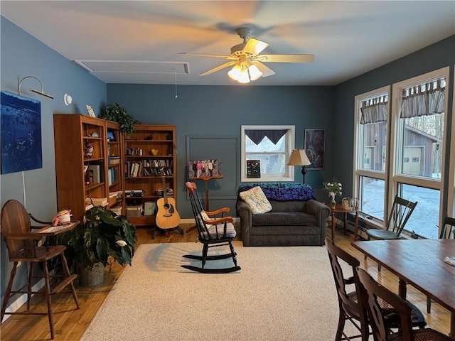 living area featuring attic access, a ceiling fan, and wood finished floors