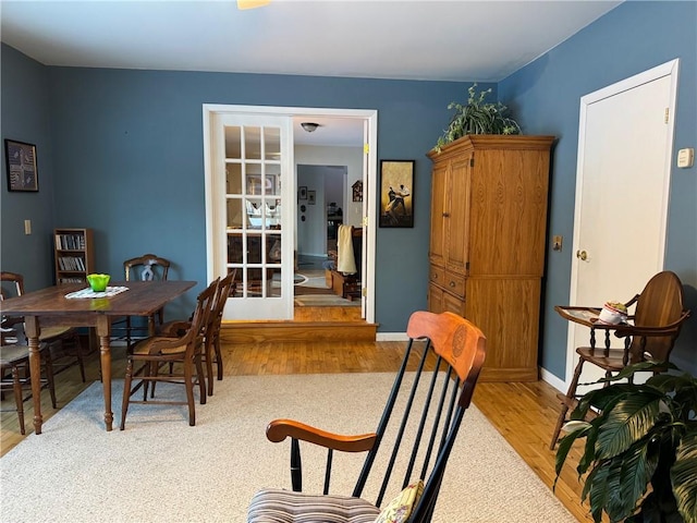 dining space featuring wood finished floors, baseboards, and french doors