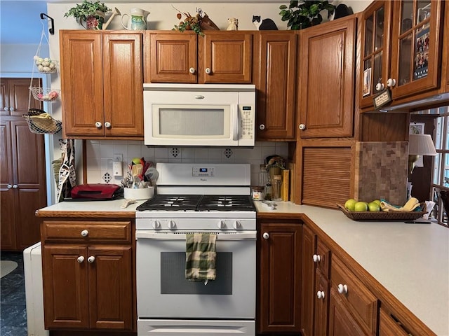 kitchen with glass insert cabinets, white appliances, brown cabinetry, light countertops, and decorative backsplash