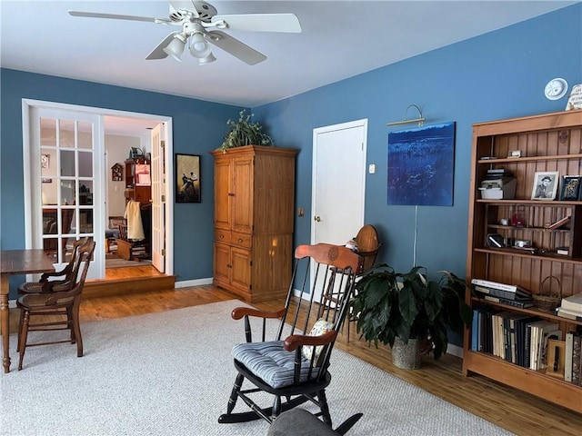 living area featuring ceiling fan, baseboards, and wood finished floors