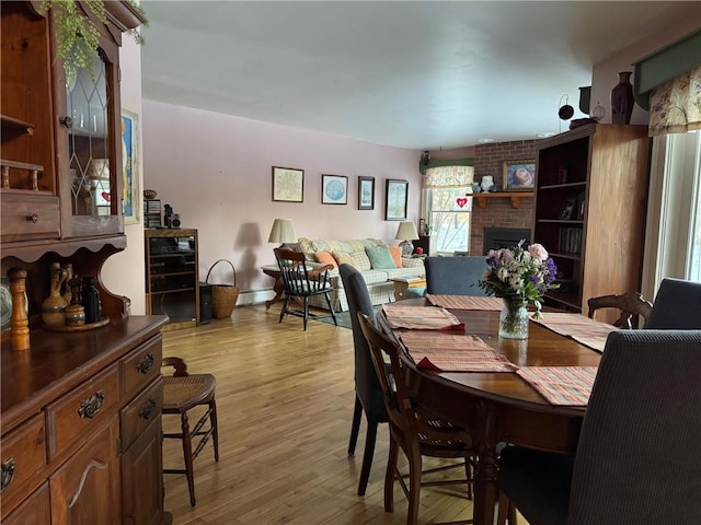 dining area featuring a fireplace, a baseboard heating unit, and light wood-type flooring