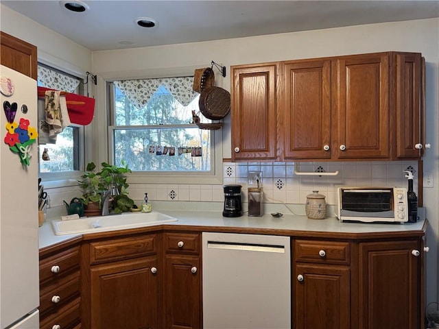 kitchen with backsplash, a toaster, plenty of natural light, white appliances, and a sink