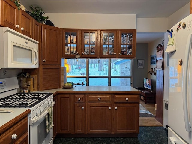 kitchen with glass insert cabinets, white appliances, and light countertops