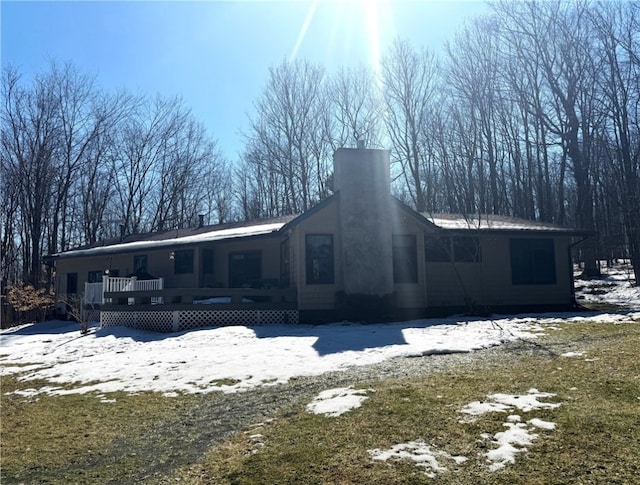 snow covered back of property with a chimney