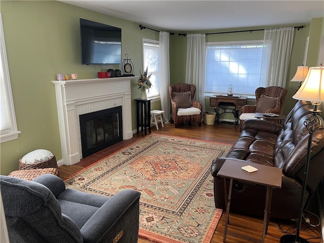 living room with a glass covered fireplace, baseboards, and wood finished floors