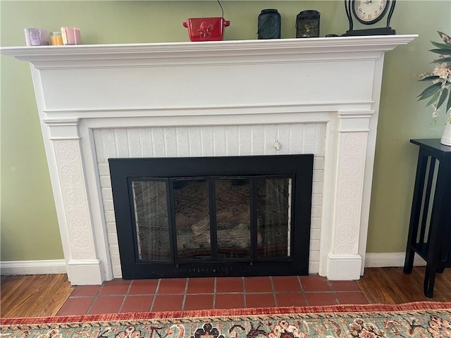 room details with baseboards, wood finished floors, and a tiled fireplace