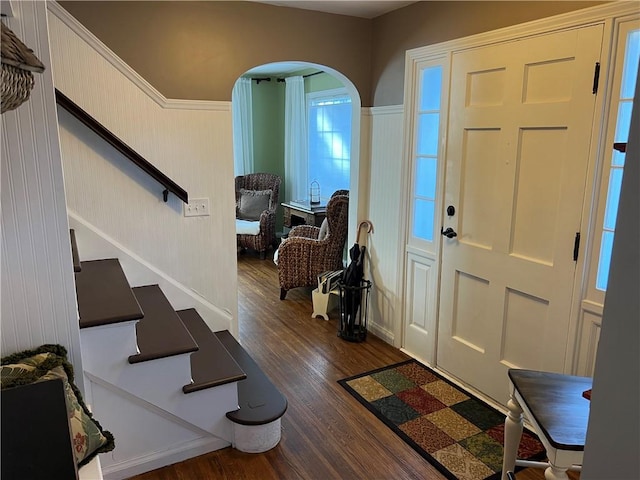 entrance foyer featuring arched walkways, wood finished floors, and stairs