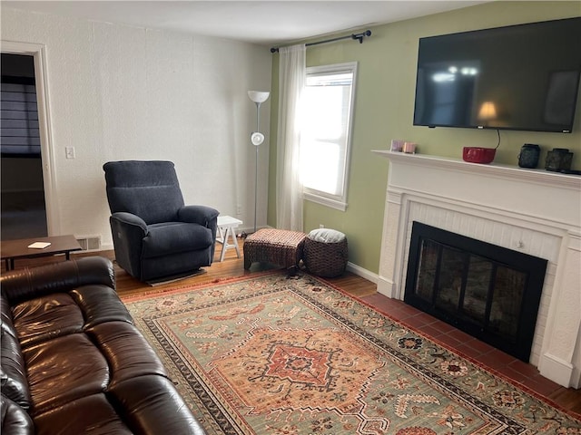 living area with visible vents, a fireplace, baseboards, and wood finished floors