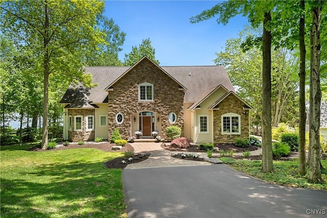 view of front of house featuring aphalt driveway, stone siding, and a front lawn