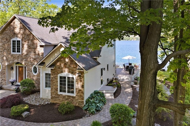 view of side of home with stone siding and roof with shingles