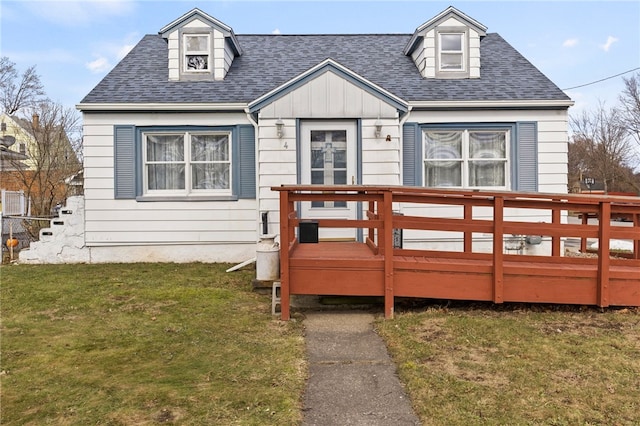 view of front of home with a wooden deck, a shingled roof, and a front lawn