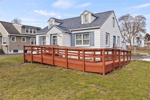 back of property with a lawn, roof with shingles, and a wooden deck