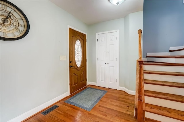 foyer with visible vents, baseboards, wood finished floors, and stairs