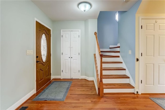 foyer entrance with baseboards, stairs, and light wood-style floors