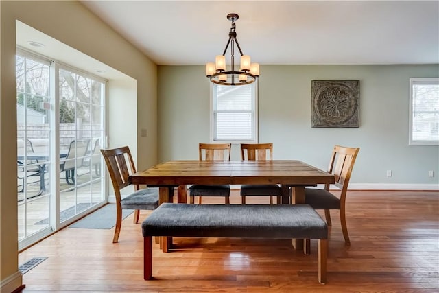 dining room with light wood-style flooring, visible vents, baseboards, and a chandelier