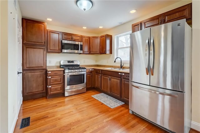 kitchen featuring visible vents, light wood finished floors, a sink, light countertops, and appliances with stainless steel finishes