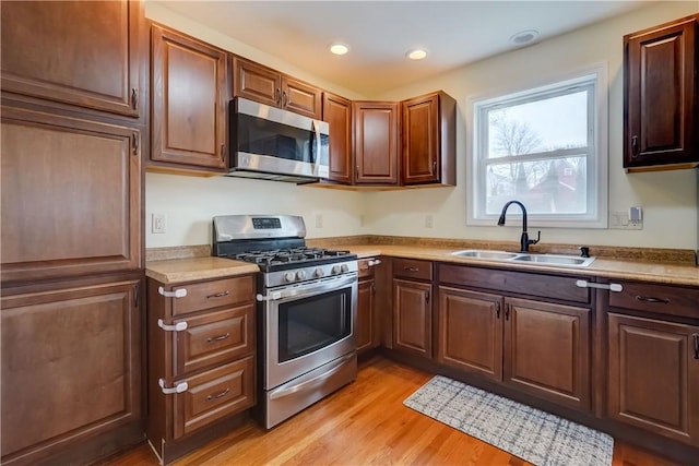 kitchen featuring light countertops, recessed lighting, light wood-style floors, stainless steel appliances, and a sink