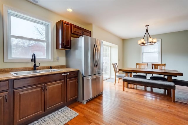 kitchen featuring light wood-style flooring, a healthy amount of sunlight, freestanding refrigerator, and a sink