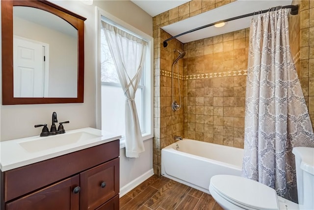 full bathroom with vanity, baseboards, wood finish floors, shower / tub combo, and toilet