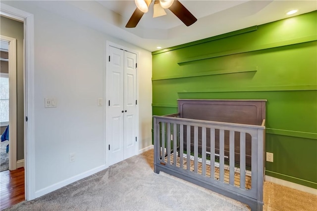 bedroom with a closet, a crib, baseboards, and carpet floors