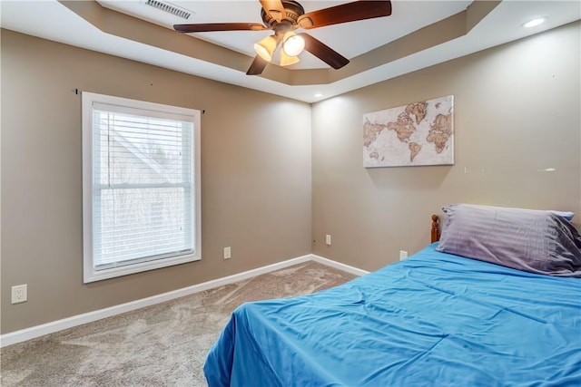 bedroom with a ceiling fan, visible vents, baseboards, a raised ceiling, and carpet flooring