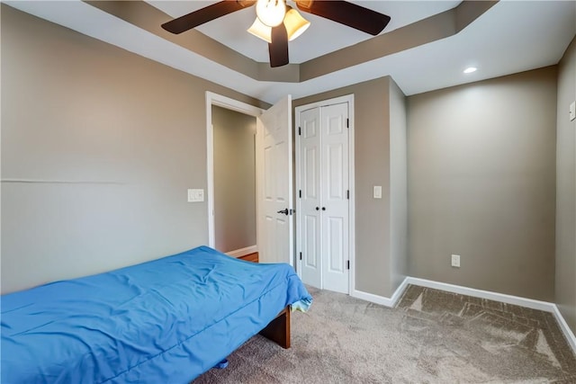 carpeted bedroom featuring a closet, baseboards, and ceiling fan