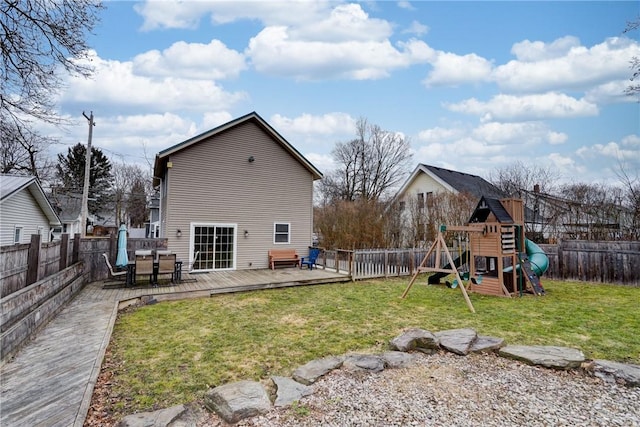 rear view of house featuring a playground, a yard, a fenced backyard, and a wooden deck