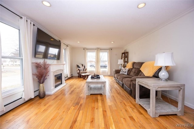 living room with ornamental molding, a glass covered fireplace, recessed lighting, light wood-style floors, and a baseboard radiator