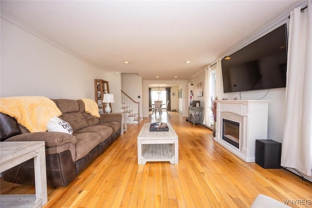 living room with recessed lighting, a glass covered fireplace, and light wood-style flooring