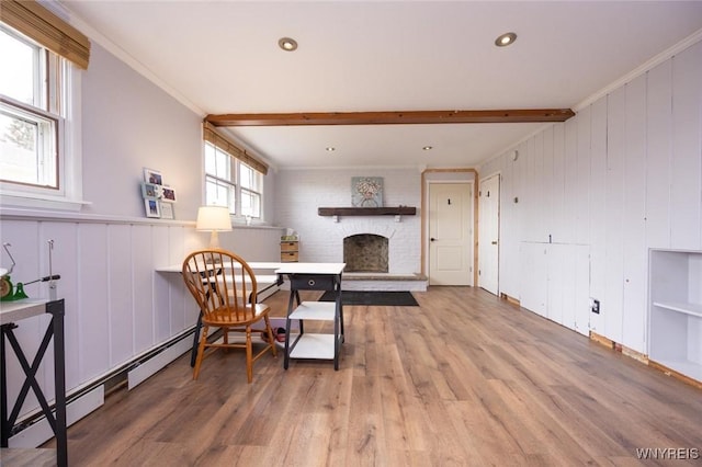 sitting room featuring beamed ceiling, a brick fireplace, wood finished floors, and ornamental molding