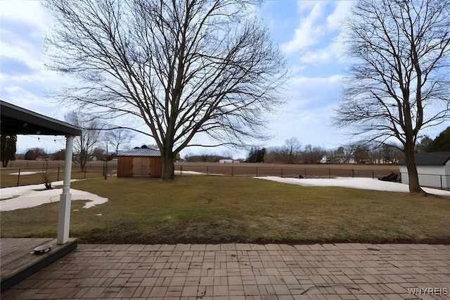 view of yard with an outbuilding, a shed, a patio area, and fence