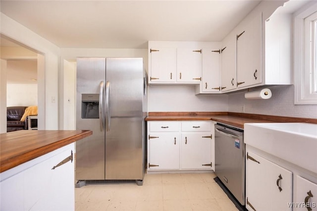 kitchen featuring wood counters, light floors, appliances with stainless steel finishes, and white cabinetry