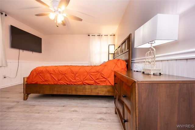 bedroom with light wood-style floors and wainscoting