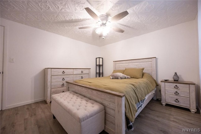 bedroom with an ornate ceiling, baseboards, wood finished floors, and a ceiling fan