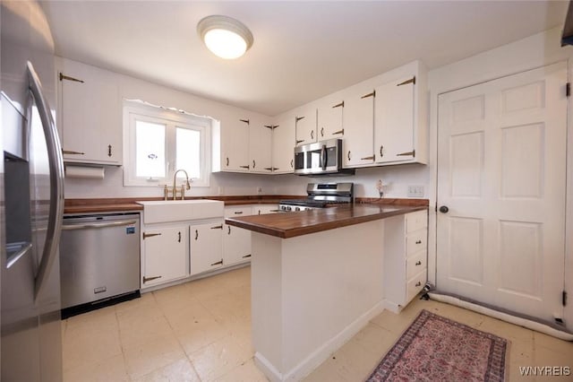 kitchen featuring a sink, stainless steel appliances, white cabinets, and wood counters