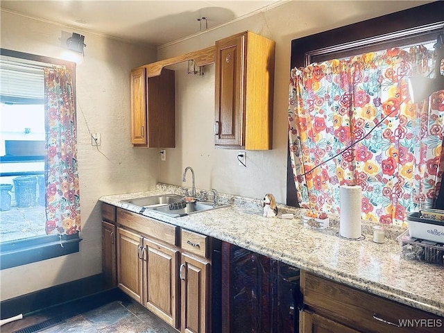 kitchen featuring a sink, baseboards, brown cabinets, and a textured wall