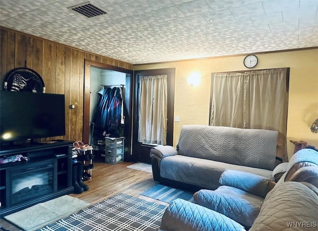 living room featuring visible vents, wooden walls, and wood finished floors