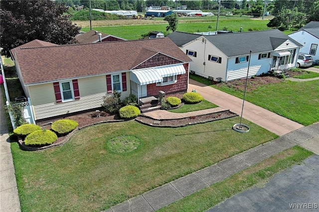 view of front of property with roof with shingles, a front lawn, and entry steps