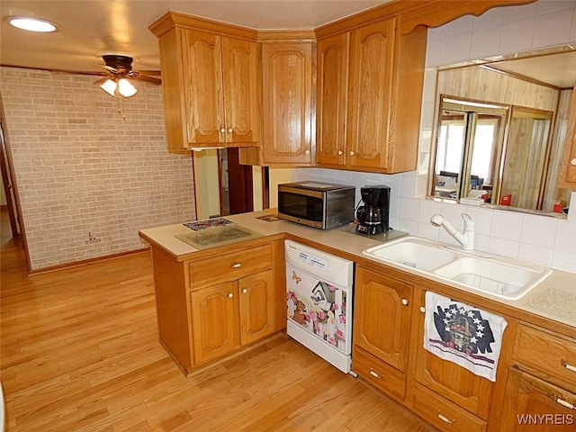 kitchen featuring a sink, light wood-type flooring, white appliances, and brick wall