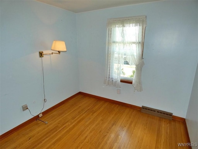 unfurnished room featuring wood finished floors, visible vents, and baseboards