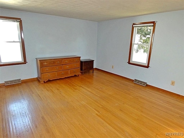 bedroom featuring light wood finished floors, visible vents, and baseboards