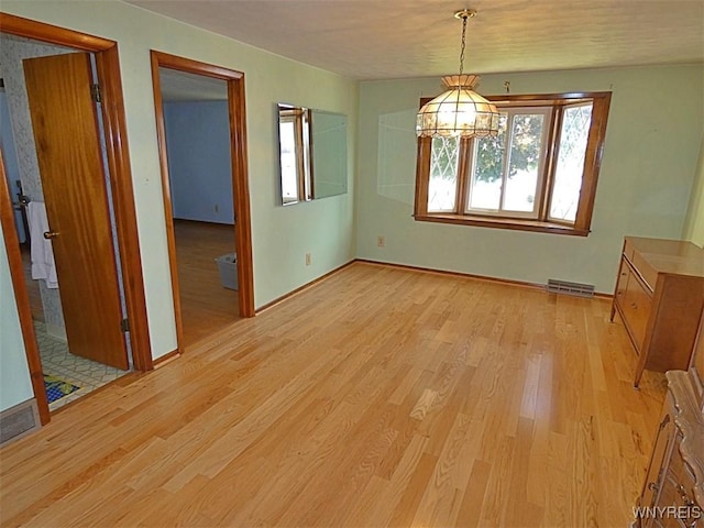 unfurnished dining area with light wood finished floors, visible vents, and baseboards